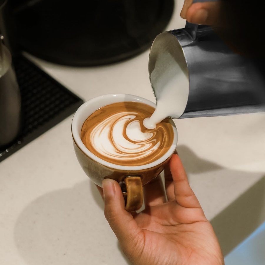 Barista pouring latte art, coffee brand detail
